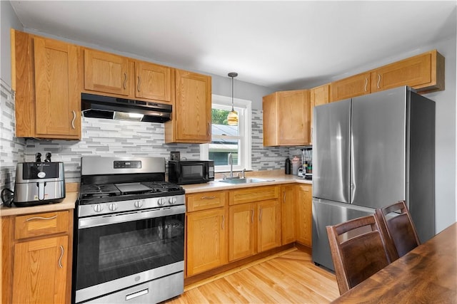 166 Midwood St, Cranston, RI 02910 - kitchen with appliances with stainless steel finishes, under cabinet range hood, light countertops, light wood-style flooring, and backsplash
