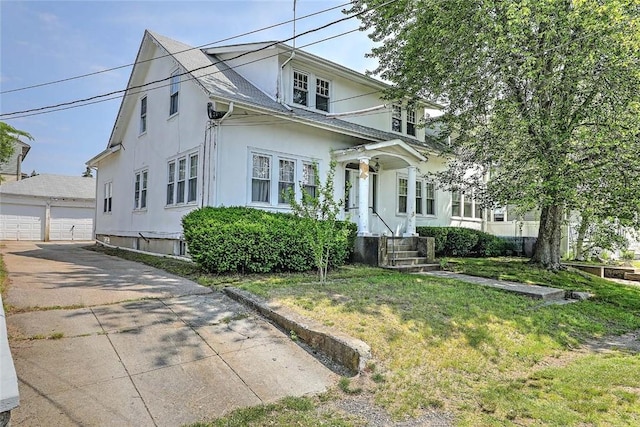 59 Colonial Ave, Cranston, RI 02910 - view of front of home featuring stucco siding, a detached garage, an outbuilding, and a front yard