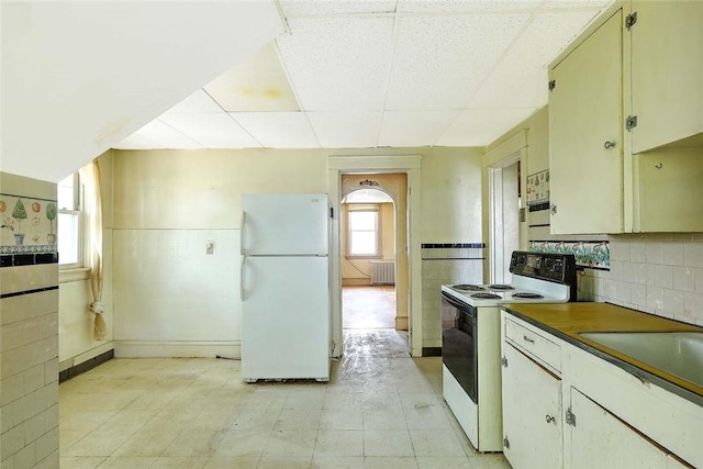 59 Colonial Ave, Cranston, RI 02910 - kitchen featuring white appliances, radiator, wainscoting, dark countertops, and a paneled ceiling