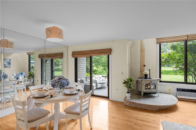 180 Fishing Cove Rd, North Kingstown, RI 02852 - dining area with a wood stove, light wood-style flooring, and an AC wall unit