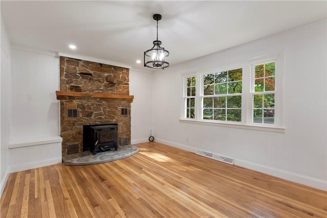 226 Quaker Ln, Scituate, RI 02857 - unfurnished living room featuring wood-type flooring, a wood stove, and a chandelier