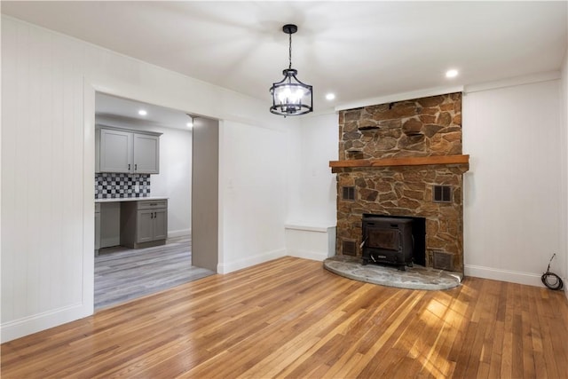 226 Quaker Ln, Scituate, RI 02857 - unfurnished living room with light wood-style floors, a wood stove, and a chandelier