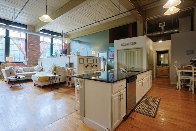 685 Social St Unit 103, Woonsocket, RI 02895 - kitchen with stainless steel dishwasher, dark countertops, white cabinetry, light wood-style floors, and a high ceiling