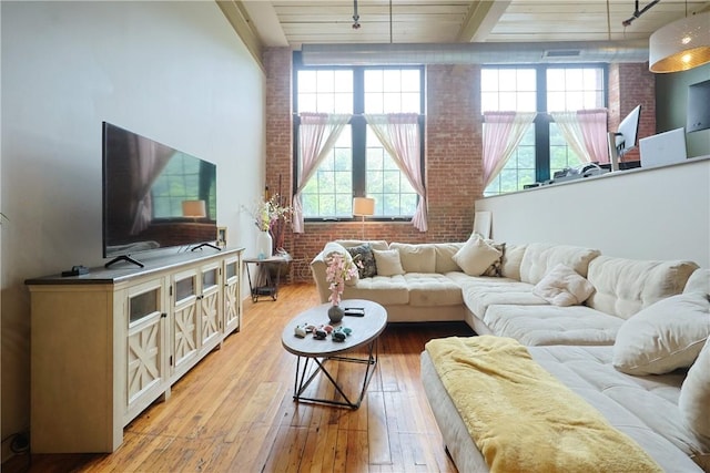 685 Social St Unit 103, Woonsocket, RI 02895 - living area with brick wall, light wood-style flooring, track lighting, plenty of natural light, and a towering ceiling