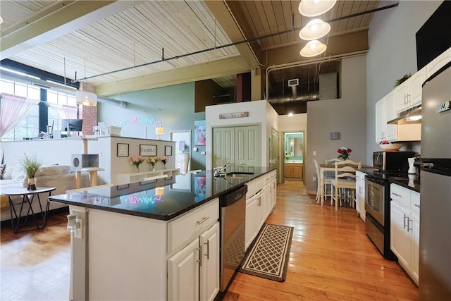 685 Social St Unit 103, Woonsocket, RI 02895 - kitchen with stainless steel appliances, white cabinetry, a center island with sink, under cabinet range hood, and a towering ceiling