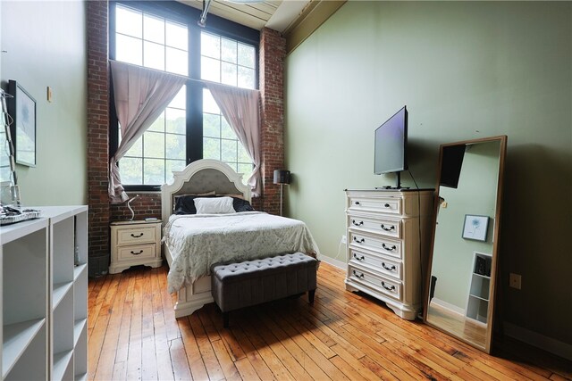 685 Social St Unit 103, Woonsocket, RI 02895 - bedroom featuring light wood finished floors, a towering ceiling, brick wall, and multiple windows