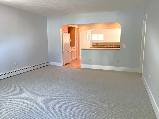 10 Cavalier Rd, Narragansett, RI 02882 - empty room with a baseboard heating unit, light carpet, arched walkways, and a textured ceiling