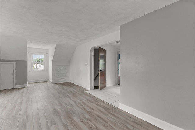 509 W Shore Rd, Warwick, RI 02889 - unfurnished living room with arched walkways, light wood-style flooring, and vaulted ceiling