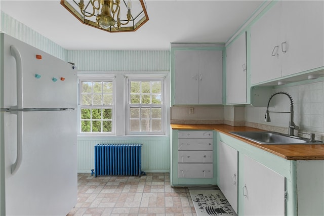 509 W Shore Rd, Warwick, RI 02889 - kitchen featuring freestanding refrigerator, radiator heating unit, a chandelier, decorative backsplash, and brick patterned flooring