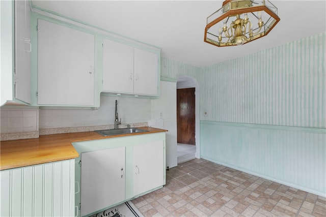 509 W Shore Rd, Warwick, RI 02889 - kitchen with wallpapered walls, arched walkways, light countertops, white cabinets, and a chandelier