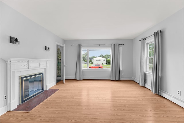 509 W Shore Rd, Warwick, RI 02889 - unfurnished living room with a baseboard heating unit, light wood-type flooring, and a glass covered fireplace