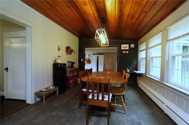 318 Saint Paul St, North Smithfield, RI 02896 - dining room featuring a baseboard heating unit, wood ceiling, wooden walls, dark stone finish flooring, and a decorative wall