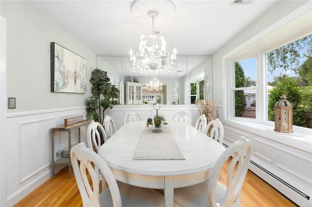 25 Rosewood Dr, North Providence, RI 02904 - dining space with a baseboard heating unit, a chandelier, light wood-style flooring, a decorative wall, and wainscoting