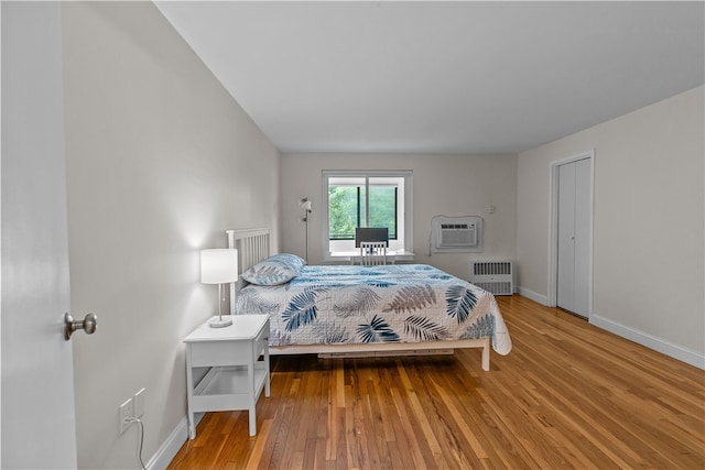 401 Bellevue Ave Unit 214, Newport, RI 02840 - bedroom featuring radiator heating unit, a wall unit AC, and wood finished floors