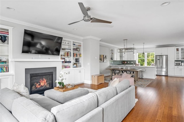 100 Algonquin Rd Unit 5, Narragansett, RI 02882 - living area featuring a ceiling fan, dark wood-style flooring, ornamental molding, a glass covered fireplace, and built in features