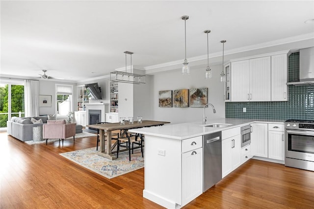 100 Algonquin Rd Unit 5, Narragansett, RI 02882 - kitchen featuring stainless steel appliances, a peninsula, a ceiling fan, a fireplace, and wood finished floors