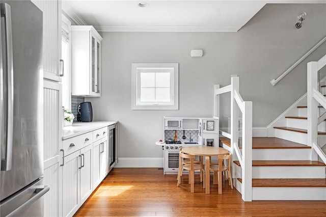 100 Algonquin Rd Unit 5, Narragansett, RI 02882 - kitchen featuring freestanding refrigerator, light wood-type flooring, backsplash, glass insert cabinets, and crown molding