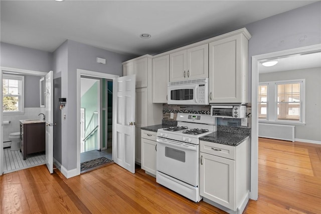 39 Owen Ave, Pawtucket, RI 02860 - kitchen featuring white appliances, white cabinetry, light wood finished floors, dark stone counters, and plenty of natural light