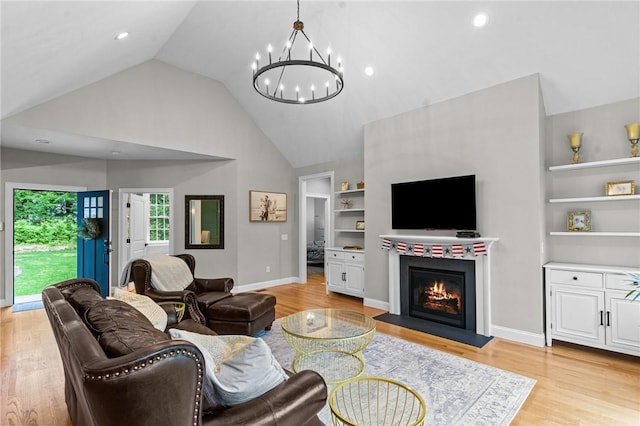 52 Pine Swamp Rd, Cumberland, RI 02864 - living room featuring a chandelier, built in features, a warm lit fireplace, high vaulted ceiling, and light wood finished floors