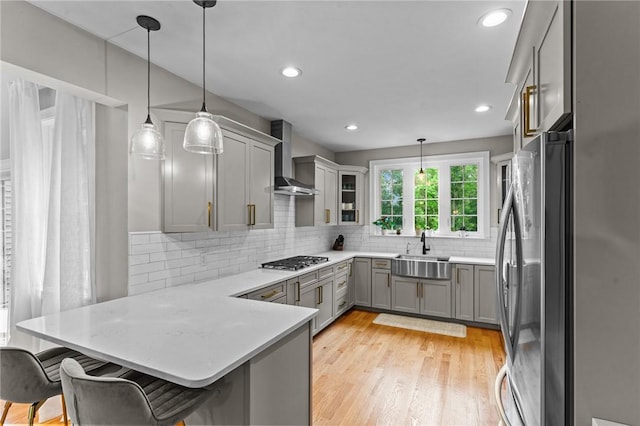 52 Pine Swamp Rd, Cumberland, RI 02864 - kitchen with appliances with stainless steel finishes, wall chimney range hood, gray cabinets, a peninsula, and light wood-type flooring