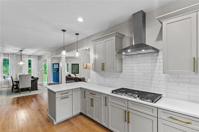 52 Pine Swamp Rd, Cumberland, RI 02864 - kitchen featuring wall chimney range hood, gray cabinets, stainless steel gas stovetop, a peninsula, and light countertops