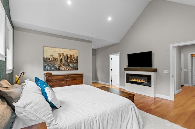 52 Pine Swamp Rd, Cumberland, RI 02864 - bedroom featuring high vaulted ceiling, a glass covered fireplace, light wood-style floors, and recessed lighting
