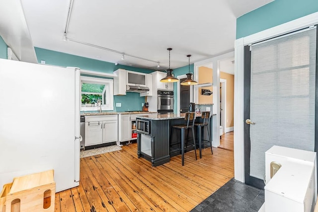 15 N St, Warwick, RI 02886 - kitchen with stainless steel appliances, track lighting, white cabinetry, a kitchen breakfast bar, and light stone counters