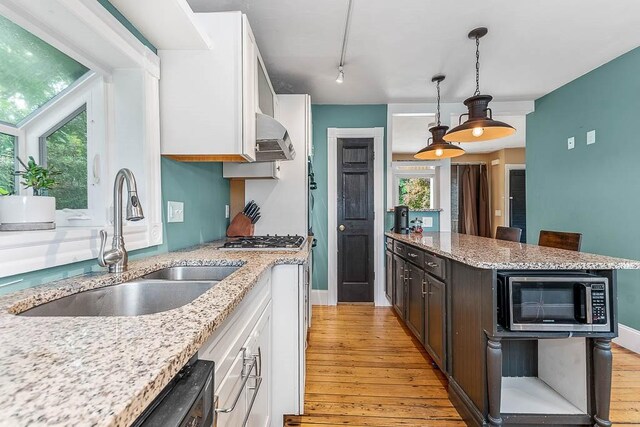 15 N St, Warwick, RI 02886 - kitchen with stainless steel appliances, light wood-style floors, white cabinetry, light stone counters, and decorative light fixtures