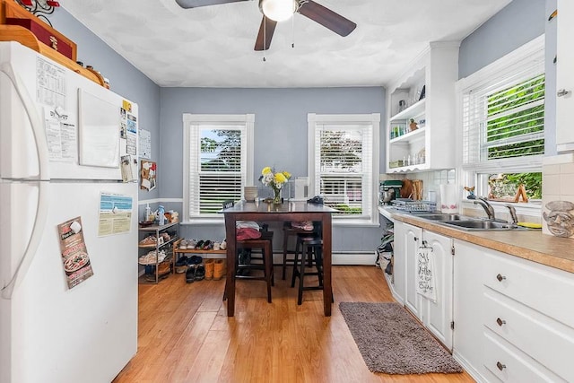 15 N St, Warwick, RI 02886 - kitchen with freestanding refrigerator, light wood-type flooring, white cabinets, a ceiling fan, and light countertops