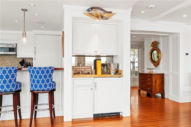 19 Defenders Row Unit 19, Newport, RI 02840 - bar area featuring stainless steel microwave, tasteful backsplash, light wood-type flooring, pendant lighting, and recessed lighting