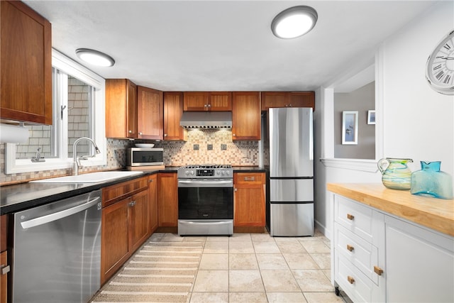 267 Fishing Cove Rd, North Kingstown, RI 02852 - kitchen with appliances with stainless steel finishes, extractor fan, tasteful backsplash, and brown cabinets
