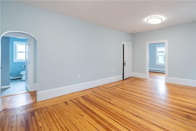 168 Waterman Ave, East Providence, RI 02914 - spare room featuring a baseboard radiator, baseboard heating, arched walkways, and light wood-style floors