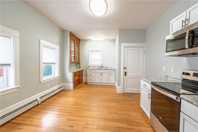 168 Waterman Ave, East Providence, RI 02914 - kitchen featuring appliances with stainless steel finishes, baseboard heating, light wood finished floors, light stone countertops, and white cabinets