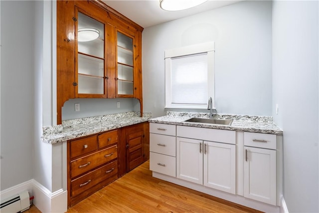 168 Waterman Ave, East Providence, RI 02914 - kitchen with baseboard heating, glass insert cabinets, light wood-type flooring, and light stone countertops