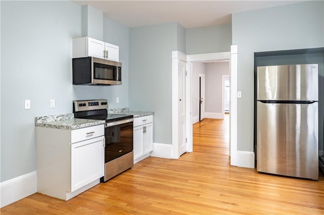168 Waterman Ave, East Providence, RI 02914 - kitchen featuring appliances with stainless steel finishes, light wood finished floors, white cabinetry, and light stone counters