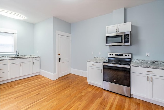 168 Waterman Ave, East Providence, RI 02914 - kitchen featuring appliances with stainless steel finishes, light wood-style floors, white cabinets, and light stone counters