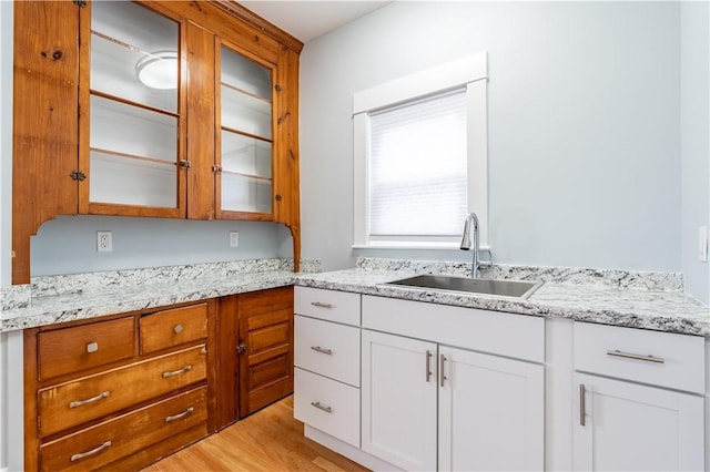168 Waterman Ave, East Providence, RI 02914 - kitchen with glass insert cabinets, light stone counters, white cabinetry, and light wood-style floors