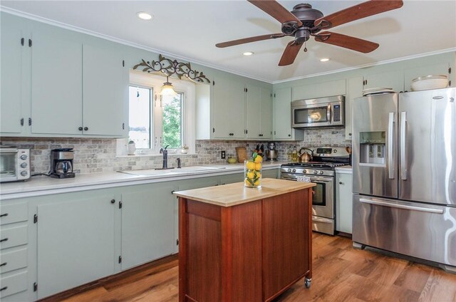 75 Columbus St, Providence, RI 02908 - kitchen featuring stainless steel appliances, ornamental molding, wood finished floors, decorative backsplash, and a kitchen island