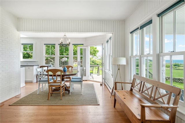 68 Grange Ave, Little Compton, RI 02837 - dining space with a chandelier, brick wall, light wood-style flooring, and a baseboard heating unit