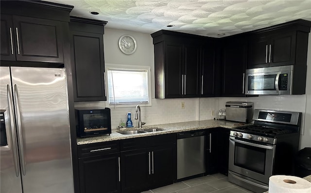 43 Toronto Ave, Providence, RI 02905 - kitchen featuring appliances with stainless steel finishes, dark cabinetry, light stone counters, and tasteful backsplash