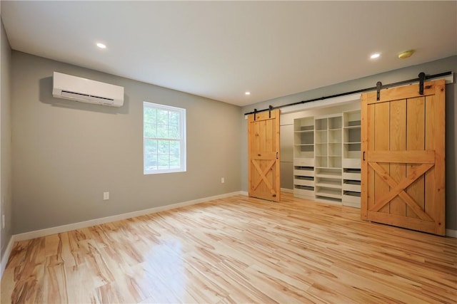 154 Foster Center Rd, Foster, RI 02825 - unfurnished bedroom with an AC wall unit, a barn door, light wood finished floors, recessed lighting, and a spacious closet