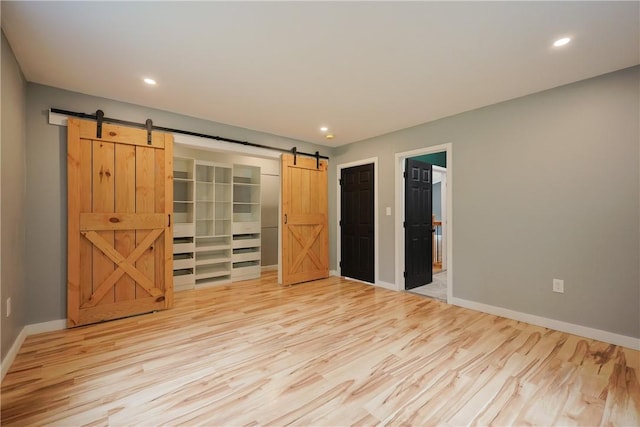 154 Foster Center Rd, Foster, RI 02825 - unfurnished bedroom featuring a barn door, light wood-style flooring, recessed lighting, a spacious closet, and a closet