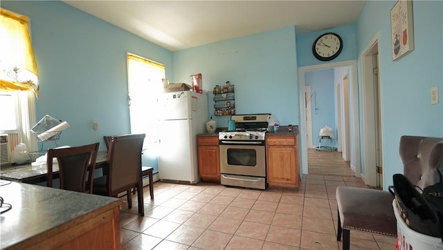 271 Union Ave, Providence, RI 02909 - kitchen with gas stove, freestanding refrigerator, light tile patterned floors, brown cabinetry, and dark countertops