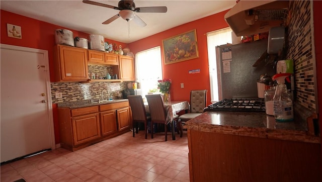 271 Union Ave, Providence, RI 02909 - kitchen featuring wall chimney exhaust hood, backsplash, a ceiling fan, light tile patterned floors, and brown cabinets