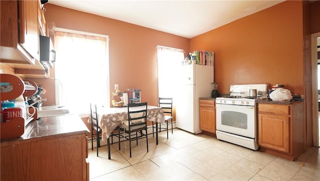 271 Union Ave, Providence, RI 02909 - kitchen featuring white appliances, dark countertops, light tile patterned floors, baseboard heating, and brown cabinets