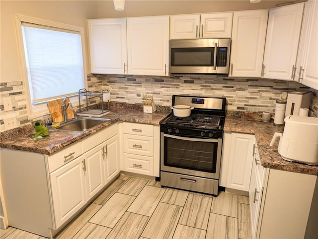 10 Stamford Ave, Providence, RI 02907 - kitchen featuring appliances with stainless steel finishes, white cabinetry, decorative backsplash, and wood tiled floors