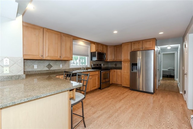 40 Lufkin Ct, Warwick, RI 02888 - kitchen featuring appliances with stainless steel finishes, light wood-style floors, a kitchen bar, backsplash, and recessed lighting