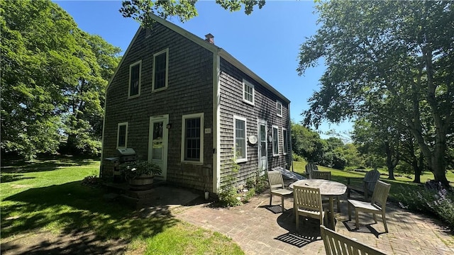 815 Beacon Hill Rd, Block Island, RI 02807 - back of house with a patio, a lawn, and a chimney