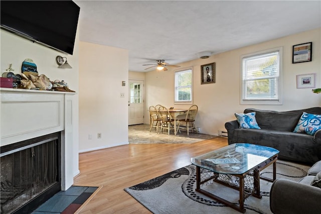 116 Balsam Rd, South Kingstown, RI 02879 - living room featuring a baseboard heating unit, wood finished floors, a ceiling fan, and a fireplace with flush hearth