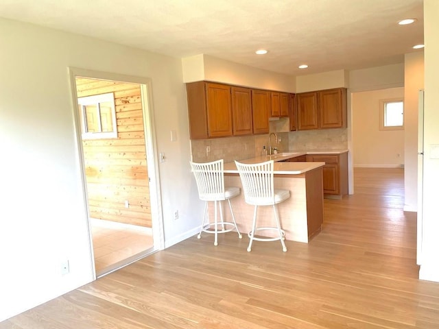 141 Sturbridge Dr, Warwick, RI 02886 - kitchen featuring a peninsula, light wood-style flooring, light countertops, a kitchen bar, and brown cabinetry